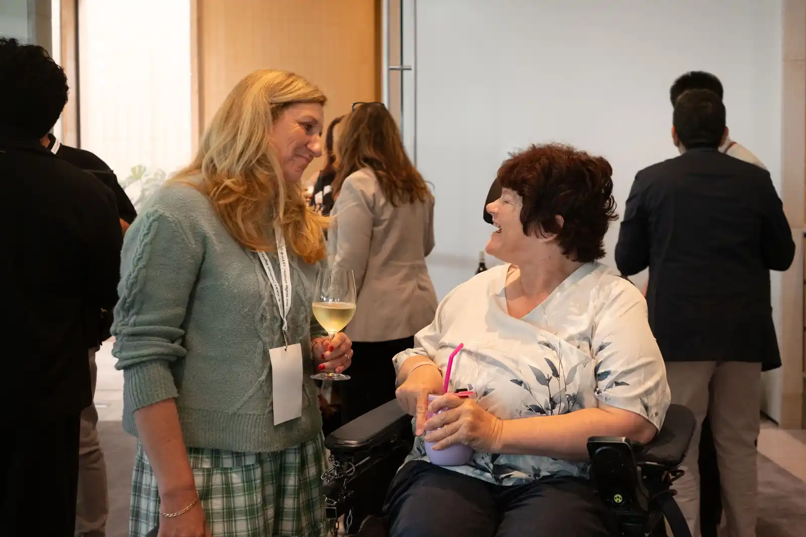 Two women talk together; one of them uses a wheelchair.