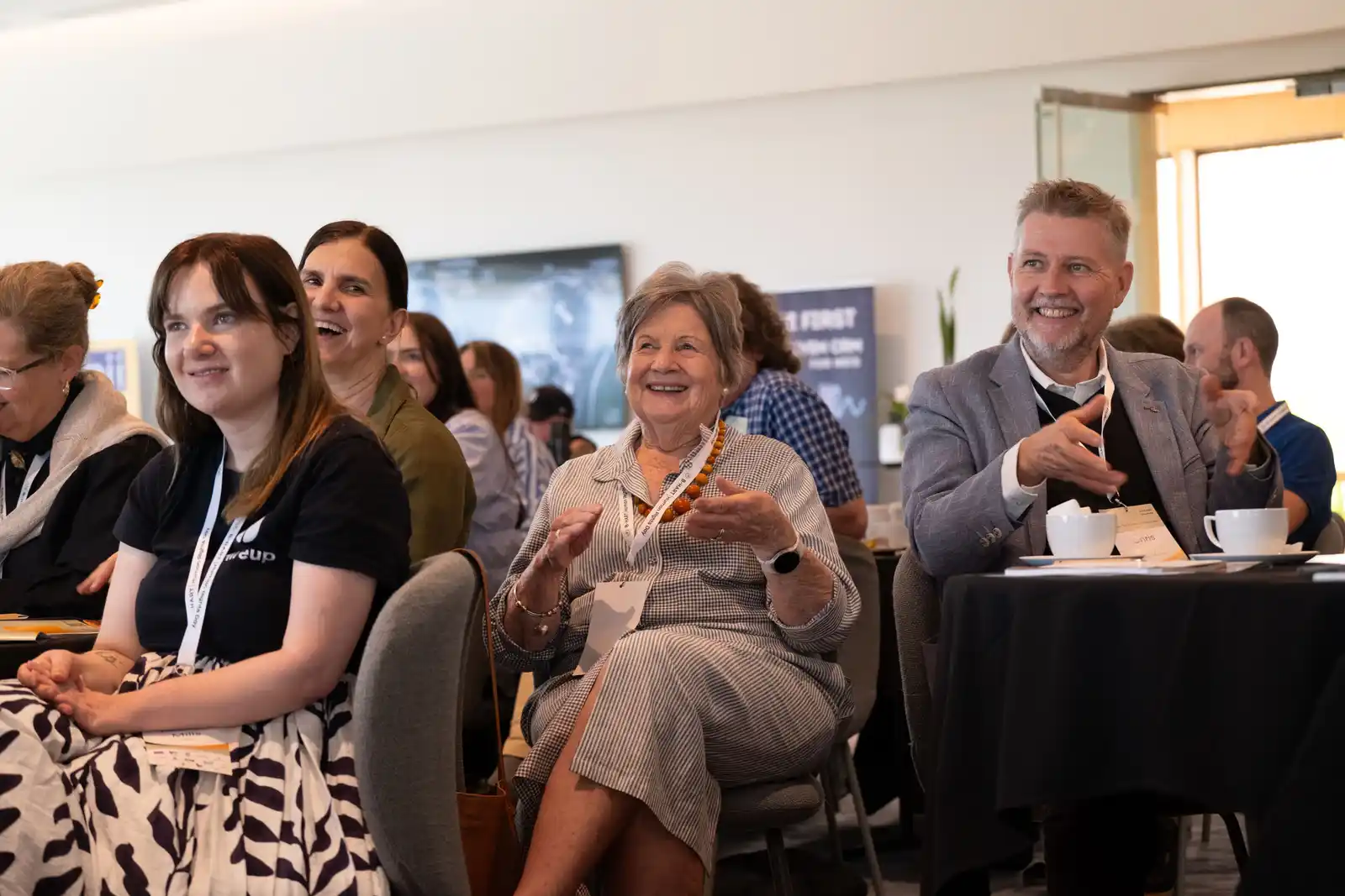 Attendees laugh together at their table during a session.