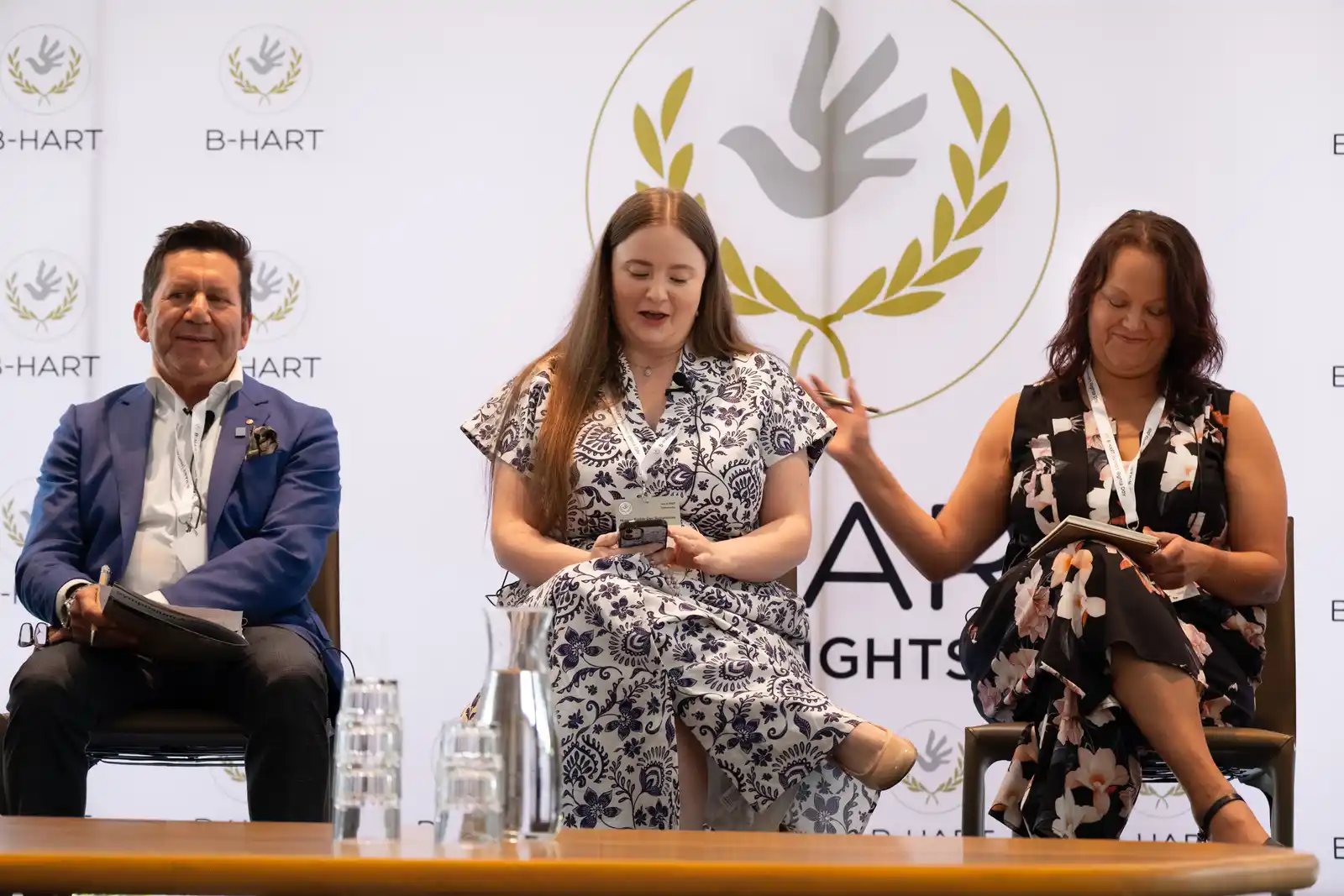 Three panellists speak on stage beneath the B-HART logo.